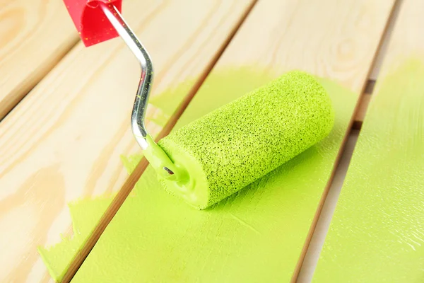 Rulle pensel med grön färg, på trä bakgrund — Stockfoto