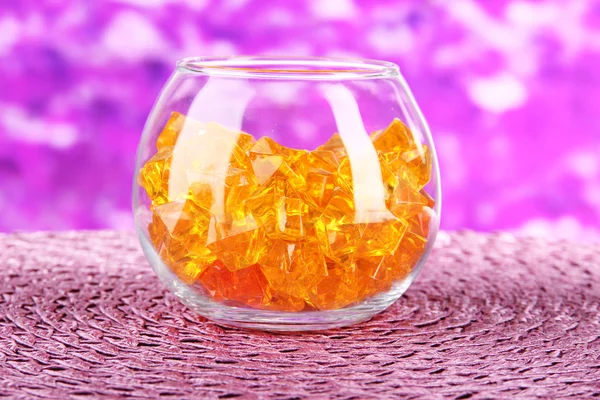 Glas met kleurrijke decoratieve stenen op lichte achtergrond — Stockfoto