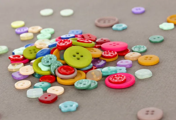 Botones de diferentes formas, tamaños y colores de primer plano sobre fondo gris — Foto de Stock