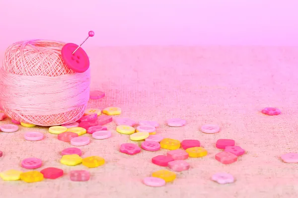 Beaux boutons et une boule de fil sur un fond rose — Photo
