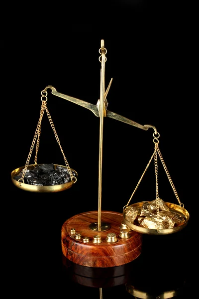 Gold and coal on scales on dark grey background — Stock Photo, Image