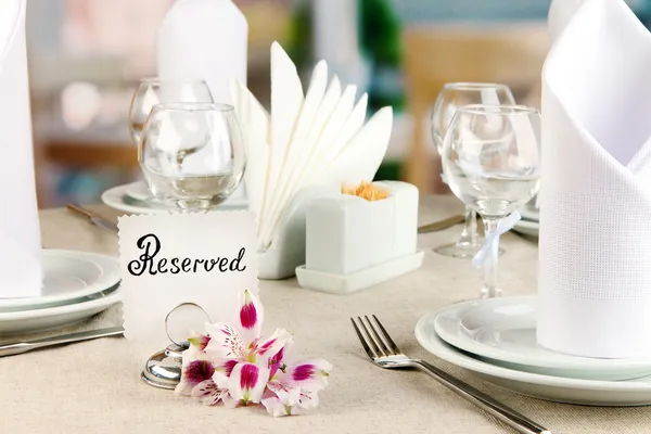 Reserved sign on restaurant table with empty dishes and glasses — Stock Photo, Image