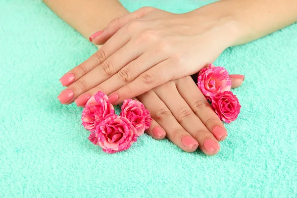 Kobieta ręce z różowy manicure i kwiaty, na kolor tła — Zdjęcie stockowe