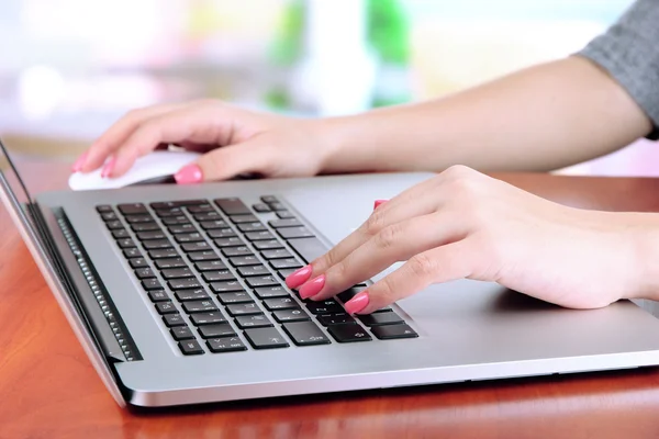 Mãos femininas escrevendo no laptop, no fundo brilhante — Fotografia de Stock