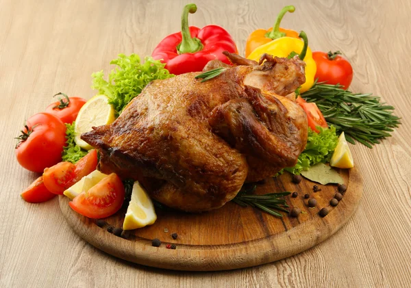 Pollo asado entero con verduras en plato, sobre mesa de madera —  Fotos de Stock