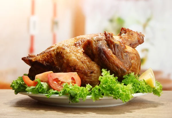 Seluruh ayam panggang dengan sayuran di piring, di atas meja kayu di kafe — Stok Foto