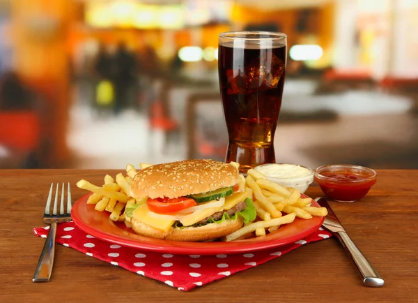 Hambúrguer de queijo saboroso com batatas fritas e bebida fria, em fundo brilhante — Fotografia de Stock