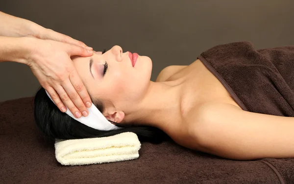 Krásná mladá žena ve spa salonu s masáž hlavy, na tmavém pozadí — Stock fotografie