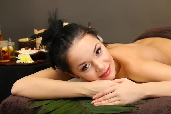 Mooie jonge vrouw in spa salon, op donkere achtergrond — Stockfoto