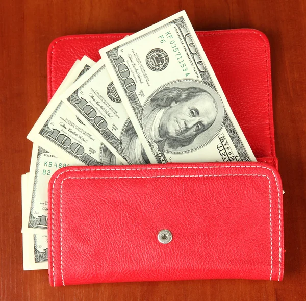 Purse with hundred dollar banknotes, on wooden background — Stock Photo, Image