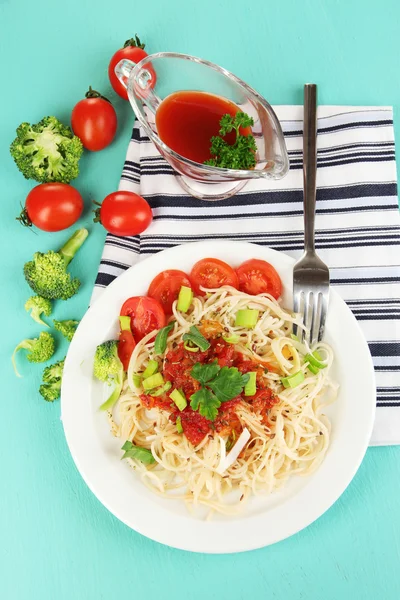 Spaghetti saporiti con salsa e verdure su piatto su tavolo di legno primo piano — Foto Stock