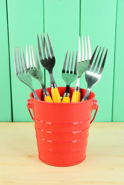 Forks in metal bucket on color wooden background — Stock Photo, Image