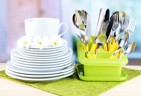 Placas, garfos, facas, colheres e outros utensílios de cozinha em guardanapo de cor, no fundo brilhante — Fotografia de Stock