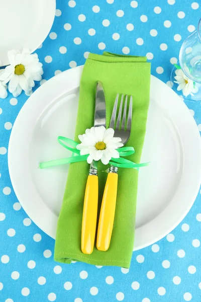 Cuchillo y tenedor envueltos en servilleta, en placa, sobre fondo de mantel de color —  Fotos de Stock