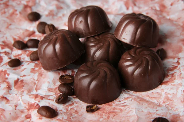 Čokoládové bonbony a kávová zrna, na barvu pozadí — Stock fotografie