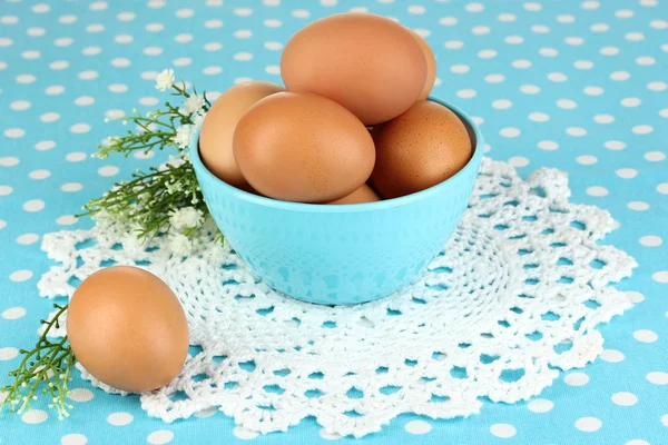 Jaja w misce na niebieski obrus z bliska — Zdjęcie stockowe