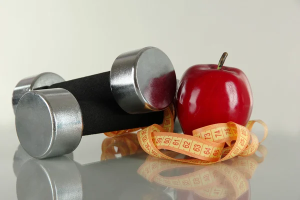 Колокольчики с яблоком и сантиметром на сером фоне — стоковое фото