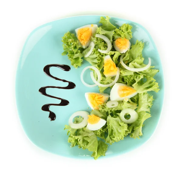 Свежий смешанный салат с яйцами, листьями салата и другими овощами на цветной тарелке, изолированный на белом — стоковое фото