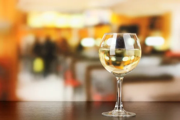 Pour something into glass with drink on wooden table on room background — Stock Photo, Image