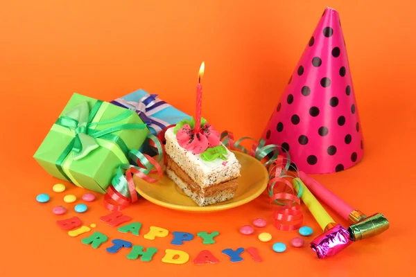 Colorful birthday cake with candle and gifts on orange background — Stock Photo, Image