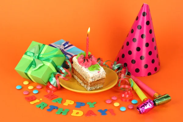 Bolo de aniversário colorido com vela e presentes no fundo laranja — Fotografia de Stock