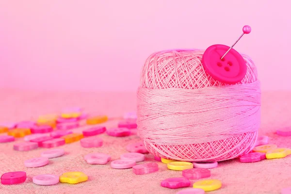 Beaux boutons et une boule de fil sur un fond rose — Photo