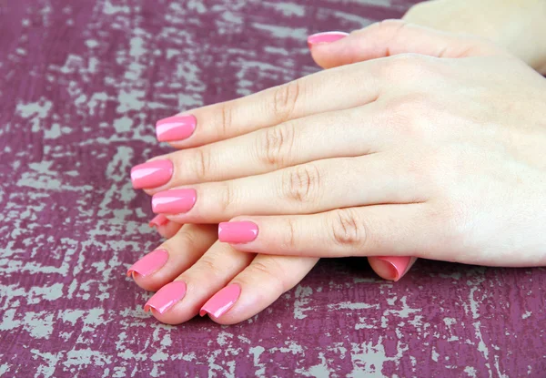 Beautiful woman hands with pink manicure, on color background — Stock Photo, Image