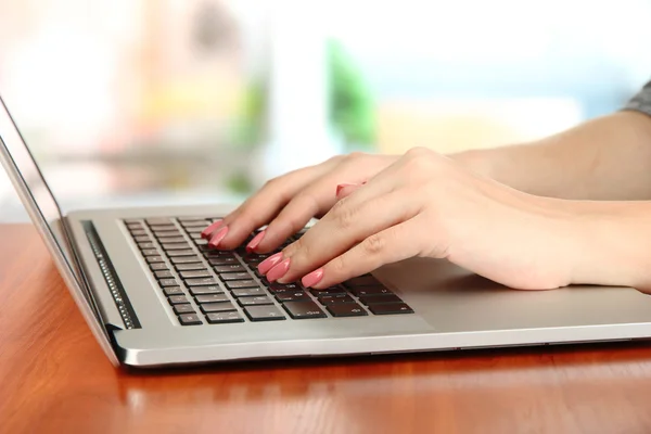 Жіночі руки пишуть на ноутбуці, на яскравому фоні — стокове фото