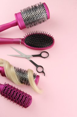 Fırçalar, pembe bir arka plan üzerinde kesme makası ve saç tarağı