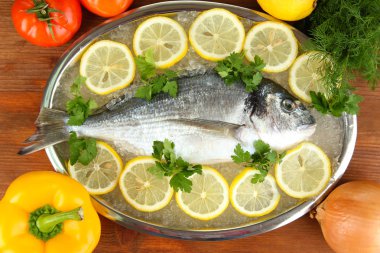 dorado fresco en tajadera con limón y verduras en la mesa de madera