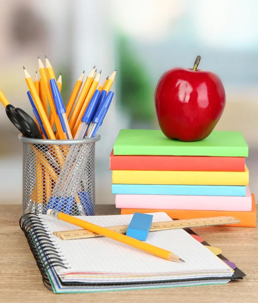 Schulbedarf mit Apfel auf Holztisch — Stockfoto