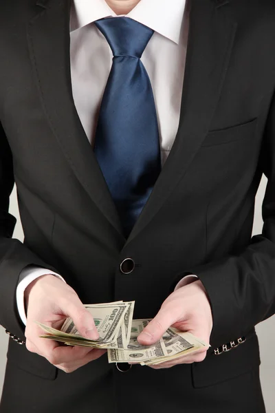 Business man counts money on grey background — Stock Photo, Image