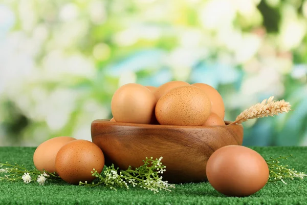 Eggs in bowl on grass on natural background — Stock Photo, Image