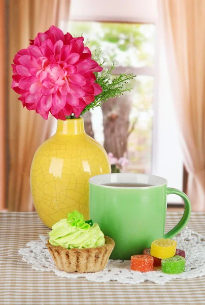 Šálky čaje s dort, cukroví a květiny na stole v pokoji — Stock fotografie