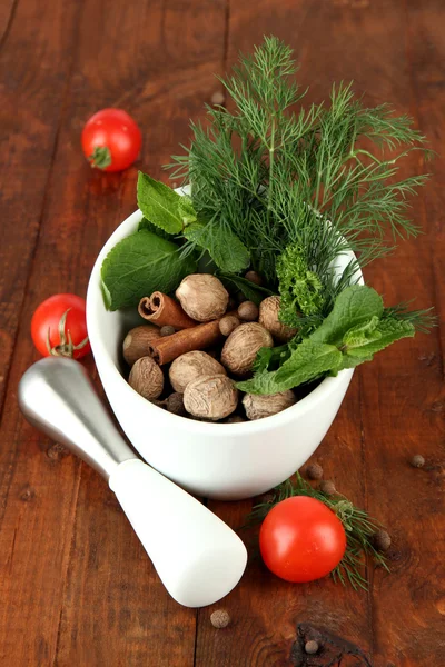 Herbs and spices in ceramic mortar, on wooden background — Stock Photo, Image