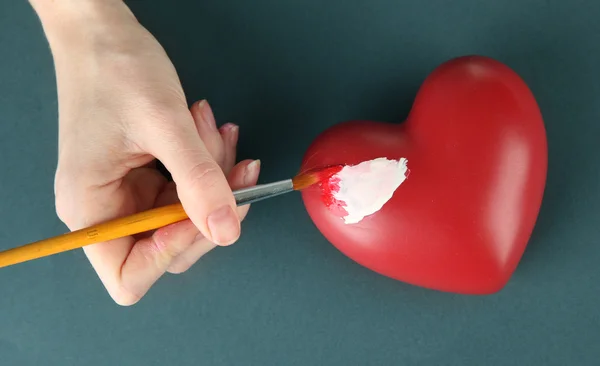 Peinture à la main tache blanche sur le cœur, sur fond de couleur. Traitement photo conceptuel des maladies cardiaques . — Photo