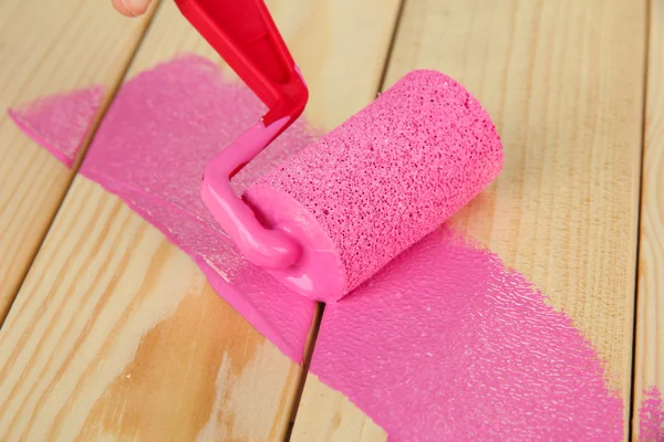 Pincel de rolo de pintura com tinta rosa, sobre fundo de madeira — Fotografia de Stock