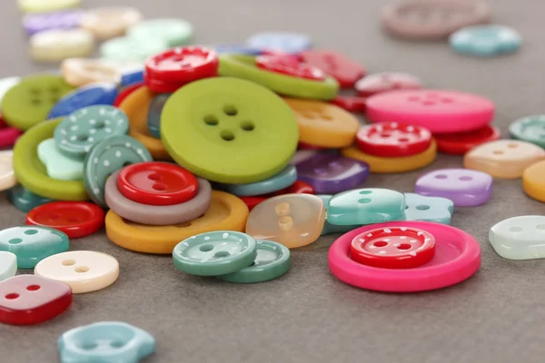 Buttons of different shapes, sizes and colors close-up on gray background — Stock Photo, Image