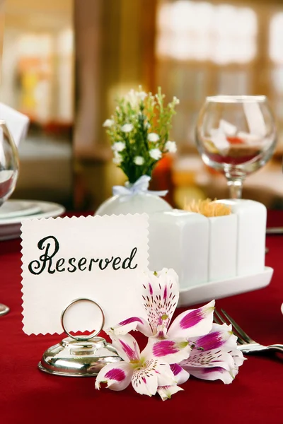 Reserved sign on restaurant table with empty dishes and glasses — Stock Photo, Image