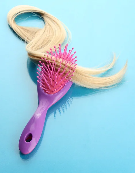 Escova de pente com cabelo, no fundo azul — Fotografia de Stock