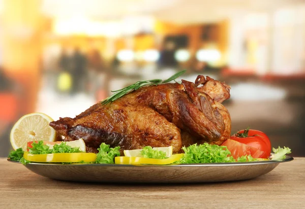 Poulet rôti entier avec légumes dans une assiette, sur une table en bois dans un café — Photo