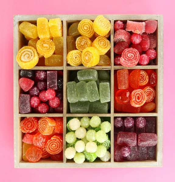 Mehrfarbige Bonbons in Holzkiste, auf farbigem Hintergrund — Stockfoto