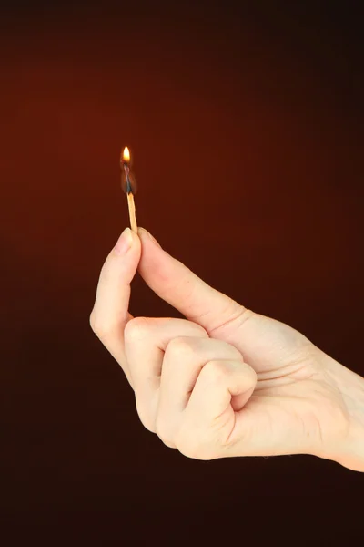 Burning match in female hand, on dark brown background — Stock Photo, Image