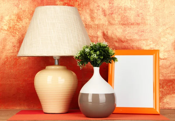 Cadre photo coloré, lampe et fleurs sur table en bois sur fond rouge — Photo