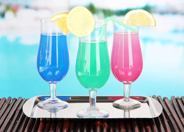 Glasses of cocktails on table near pool — Stock Photo, Image