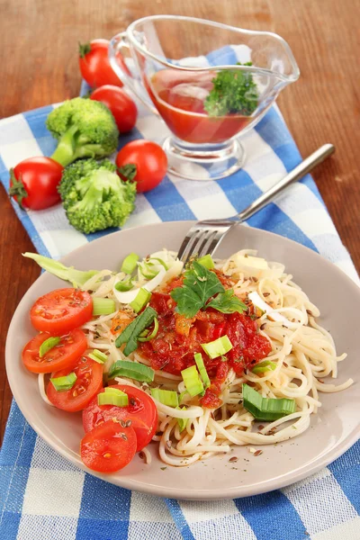 Chutné špagety s omáčkou a zeleninou na štítku na dřevěný stůl detail — Stock fotografie