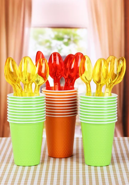 Cups, spoons and forks, of different colors on bright background — Stock Photo, Image