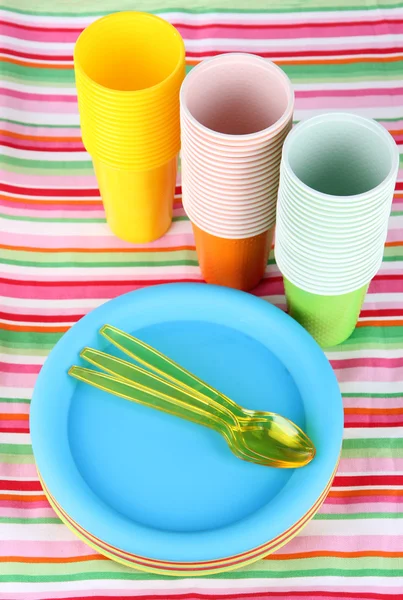 Cups, spoons and forks, of different colors on bright background — Stock Photo, Image