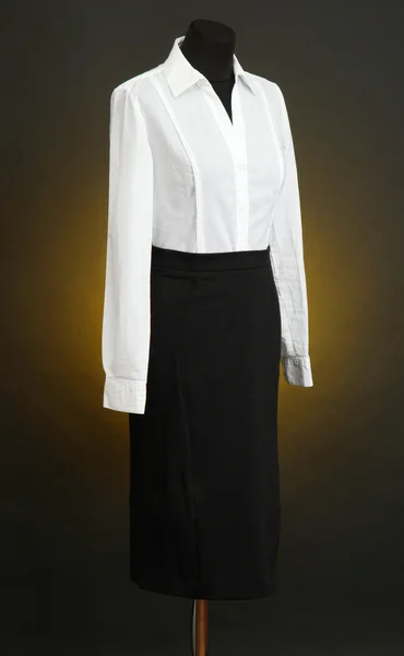 Białą bluzkę i czarną spódnicę na manekin na tle ciemnego koloru — Zdjęcie stockowe