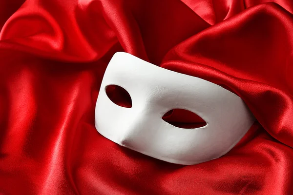 White mask, on red silk fabric — Stock Photo, Image